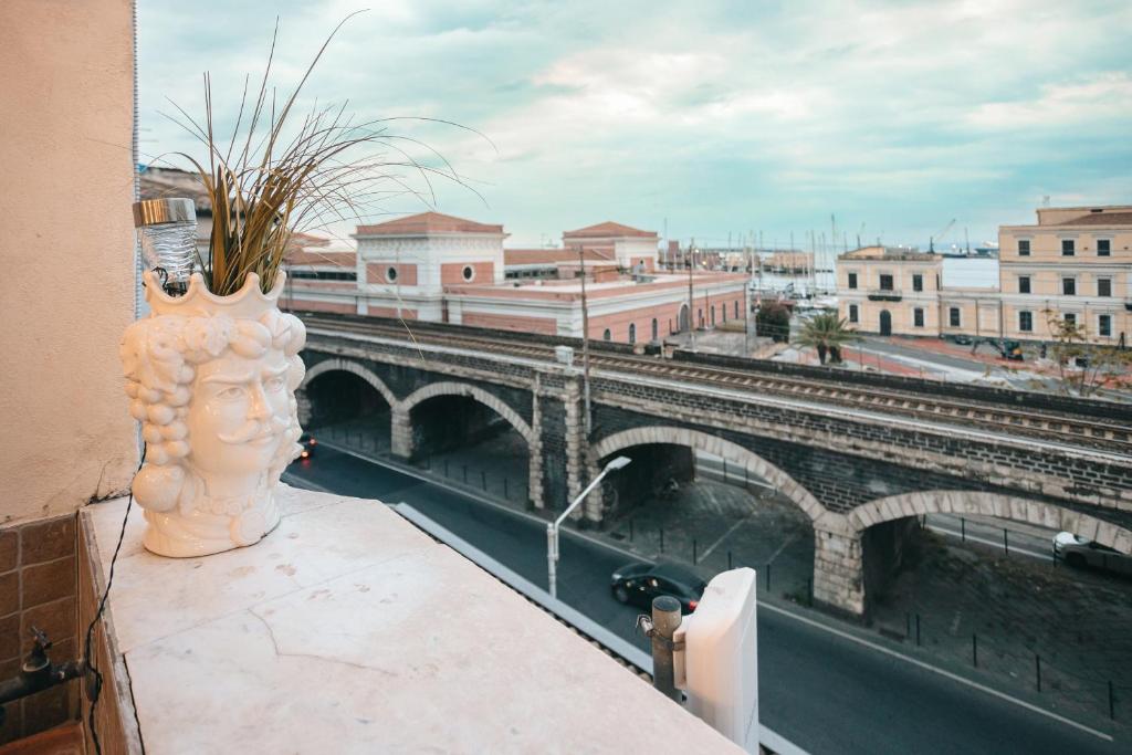 Vista dal balcone con testa di moro in primo piano, affaccio sugli storici Archi della Marina e sul porto di Catania.